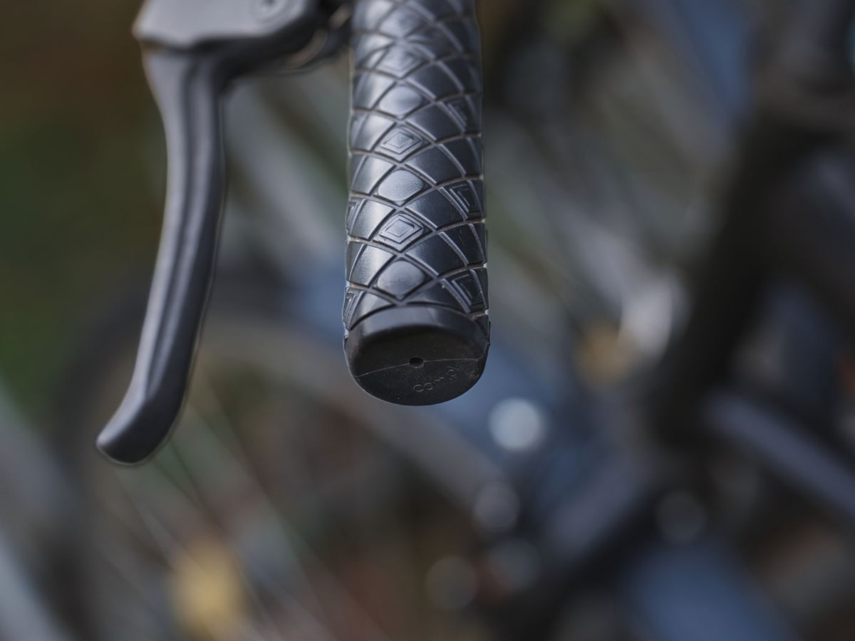 Close-up of a black textured rubber bicycle handle grip next to a brake lever
